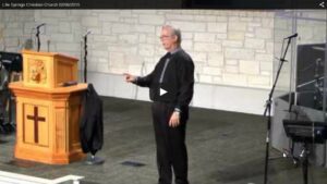 Man speaking on stage at a church podium