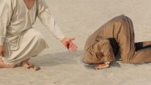 Man with head in ground on sand.