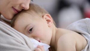 Mother lovingly breastfeeding her baby at home