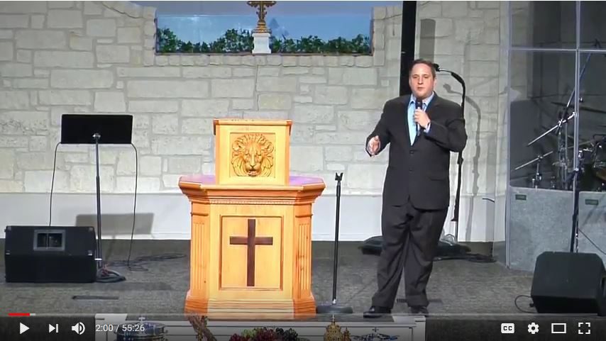 Man speaking at a church podium indoors