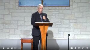 Elderly man delivering speech at church podium