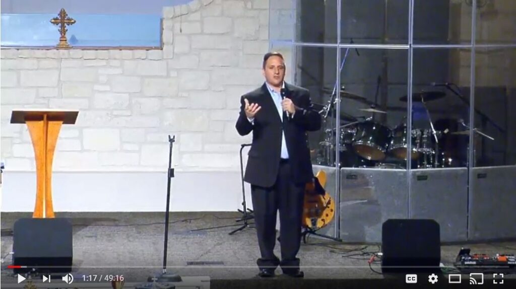 Man speaking on church stage during service.
