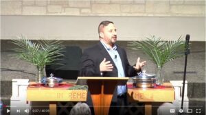 Man speaking at church podium with palms