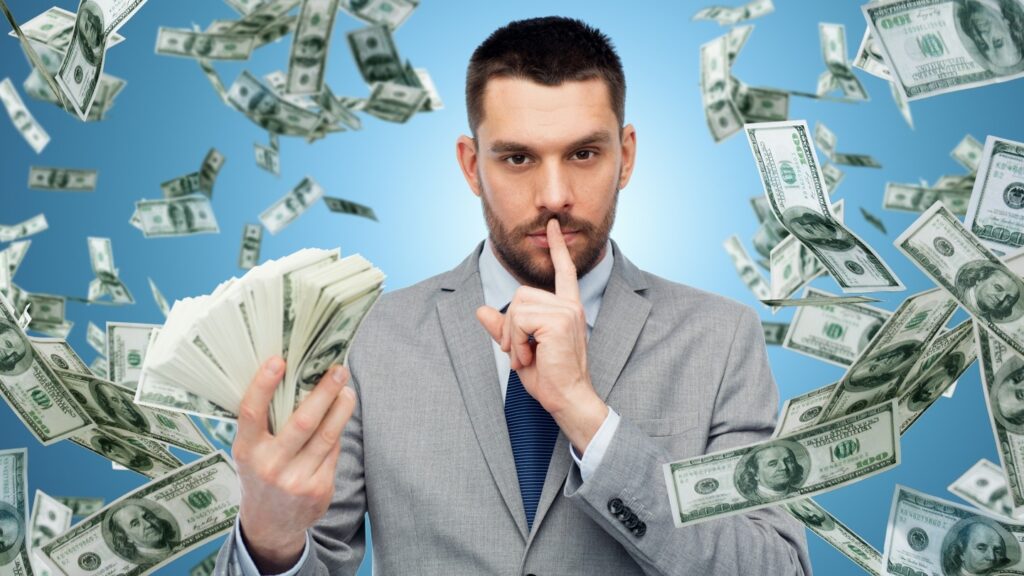 Man surrounded by money holding finger to lips