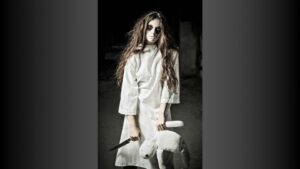 Scary woman in costume holding plush toy.