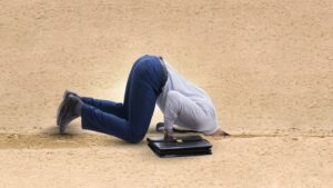 Man with head in sand and briefcase.