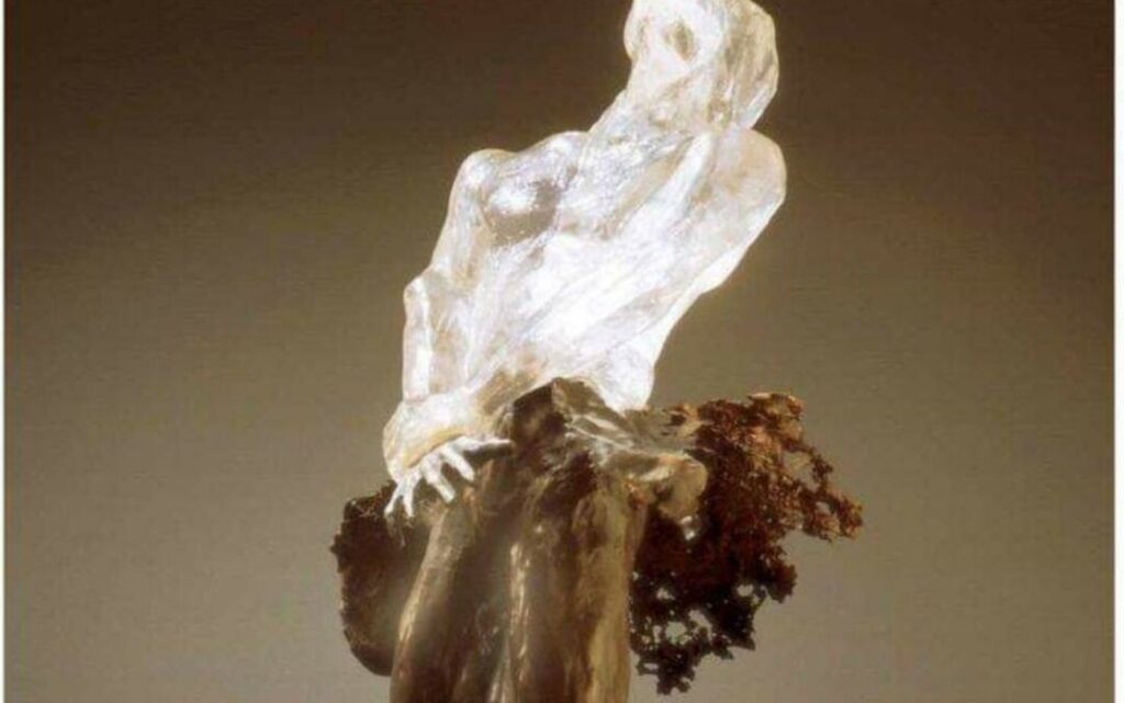 Crystal sculpture of a woman on driftwood.