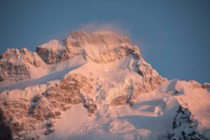 Snow-covered mountain peak during sunrise glow.