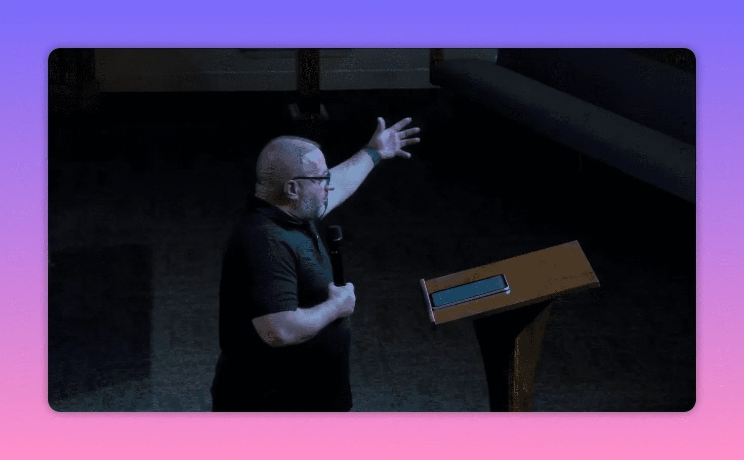 Speaker standing beside a lectern with one arm raised, delivering a point about spiritual resistance