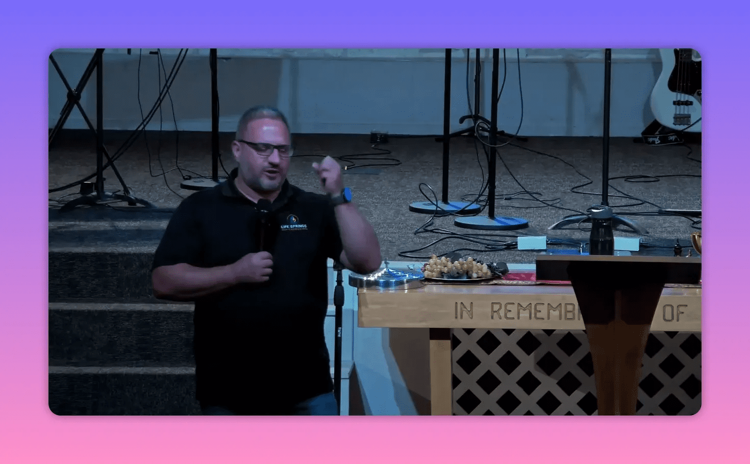 Speaker pointing toward his head while speaking beside the communion table and lectern