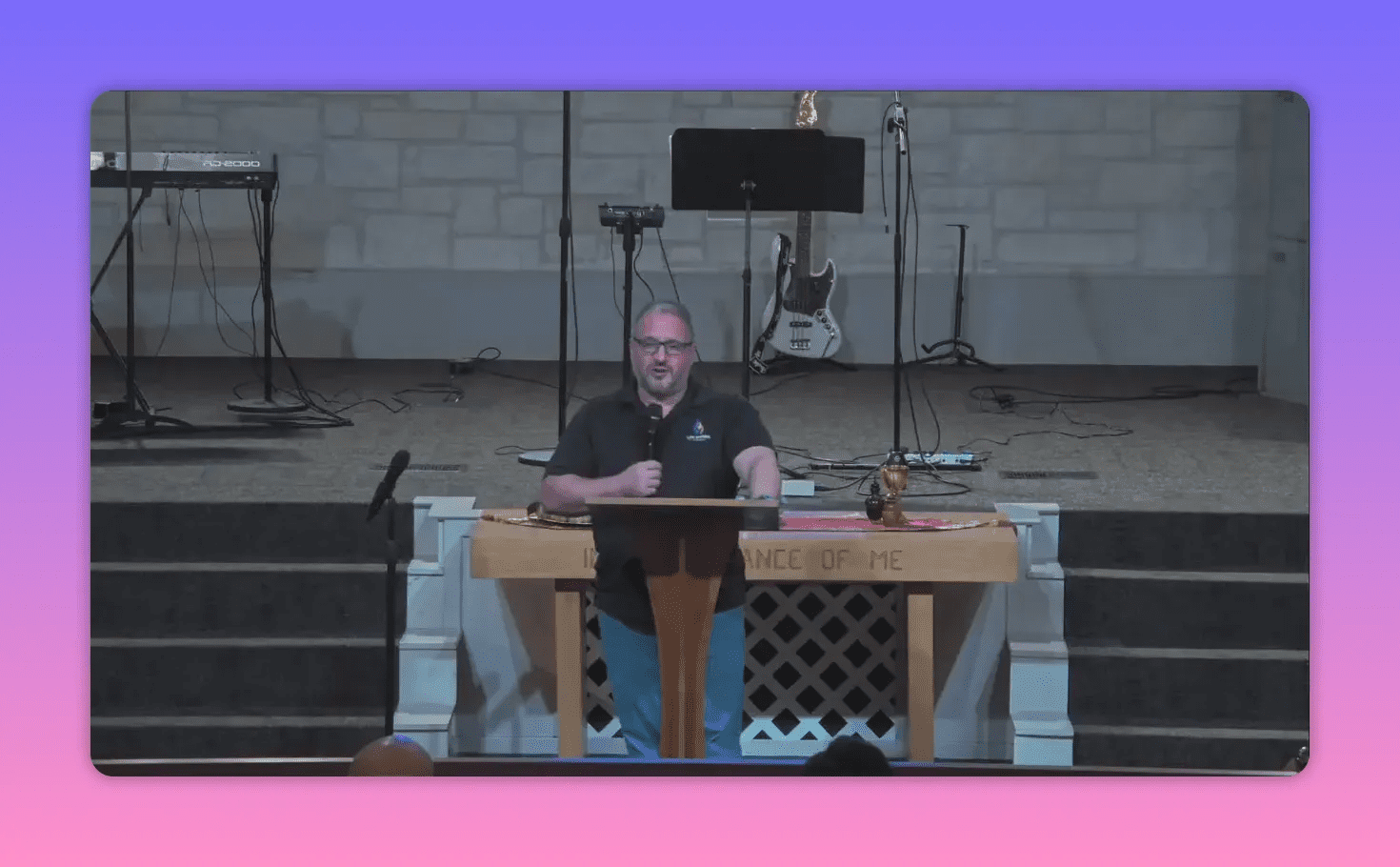 Centered pulpit shot of a speaker addressing the congregation with communion items and instruments behind