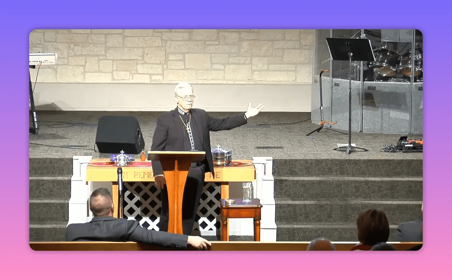 pastor at a pulpit with an open arm gesture inviting the congregation