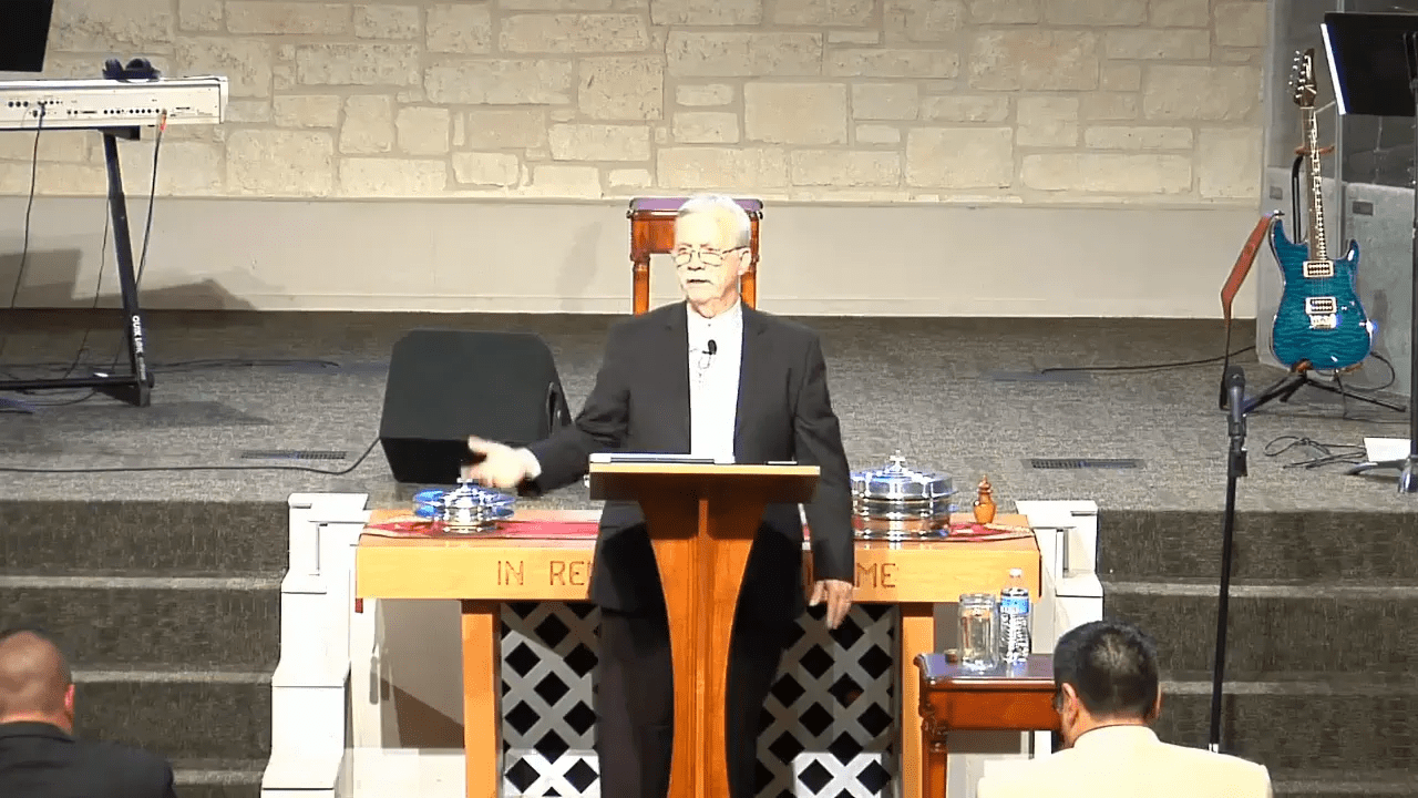 Preacher at a pulpit making an open-handed gesture while teaching, showing an engaging, relational posture