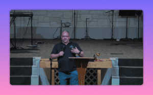 Speaker at church pulpit with communion cup on the altar and empty stage behind, mid-sermon