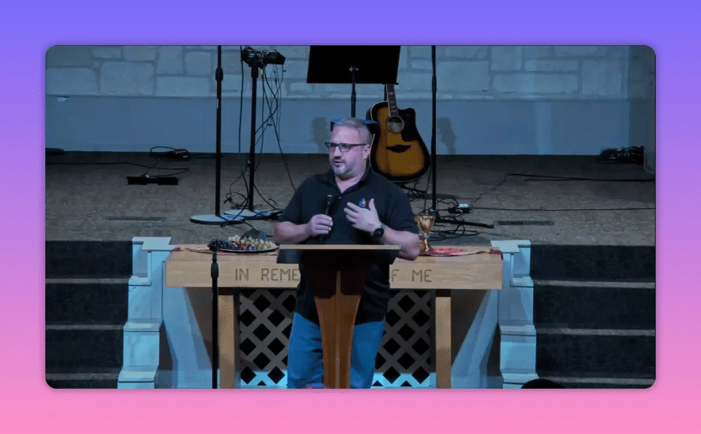 Speaker at a church lectern addressing the congregation with pulpit, communion table and guitar behind him