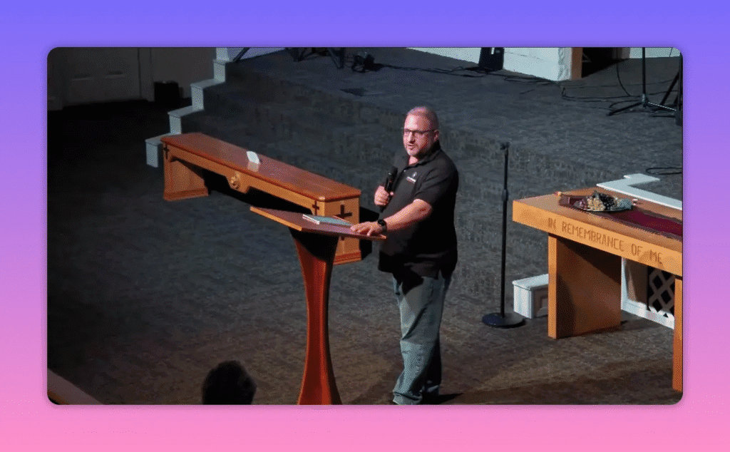 man speaking from a church pulpit holding a microphone with the altar visible