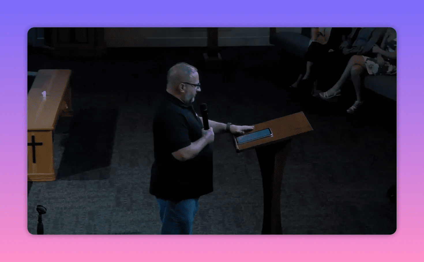 Pastor with microphone touching a tablet on the lectern while speaking to the congregation