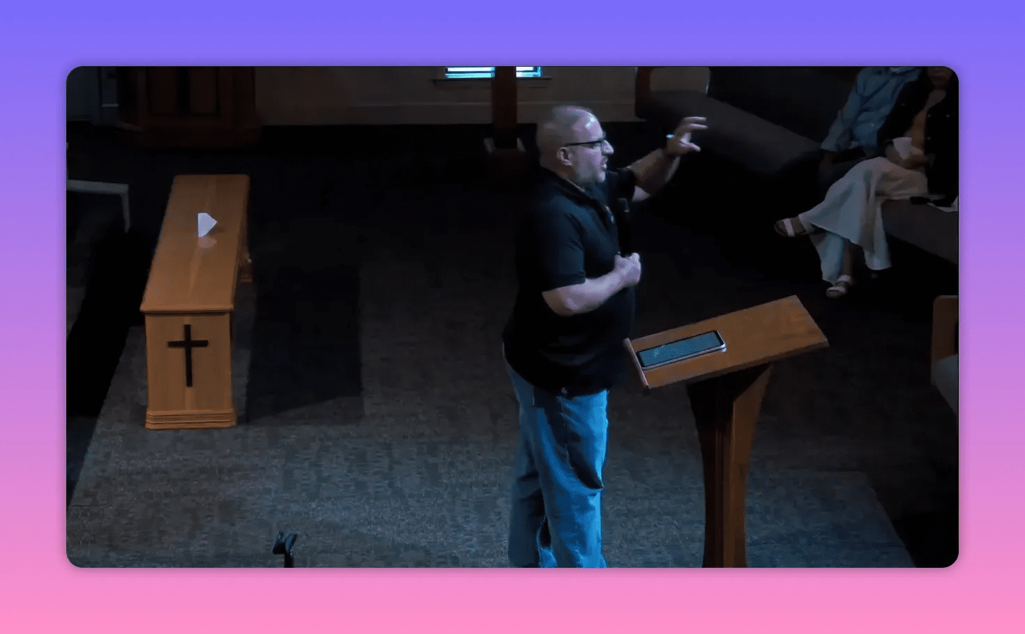 Speaker at a lectern making an illustrative hand gesture during a sermon