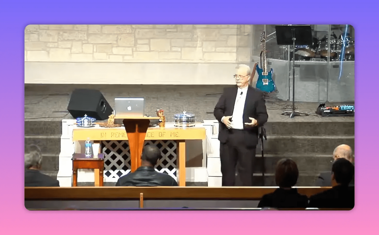 centered pulpit with showbread trays and speaker on stage, inscription 'In remembrance of me' visible