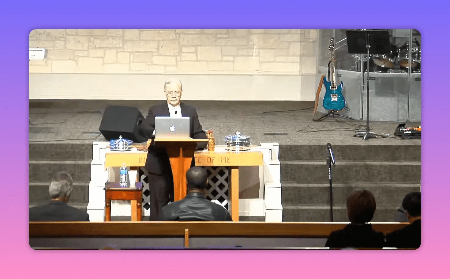 pulpit with laptop and silver showbread trays on table in front of stage