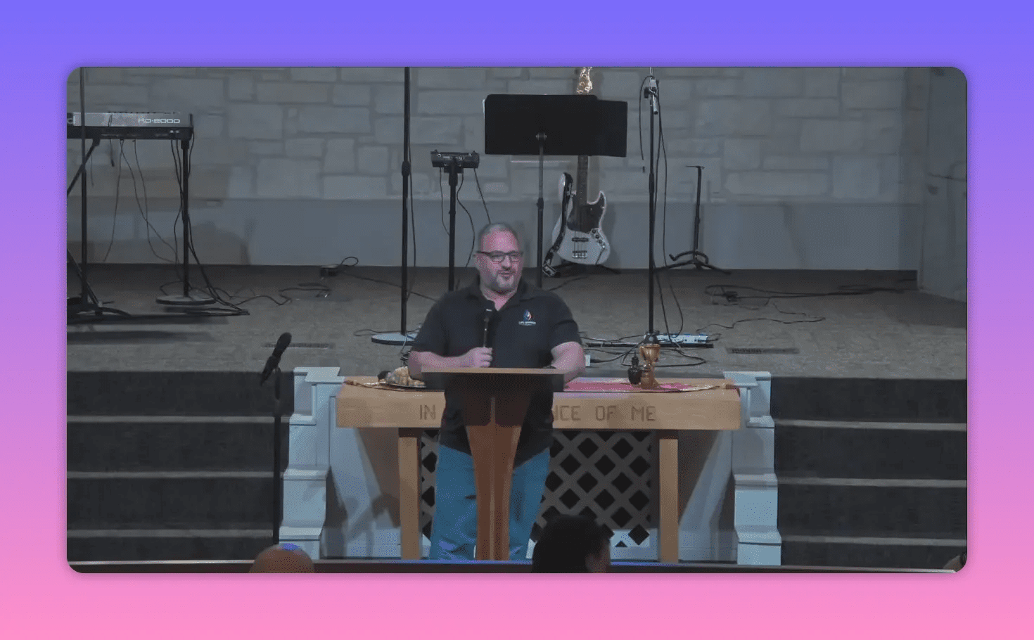 Church speaker using hand gestures at the pulpit beside a communion table and stage instruments