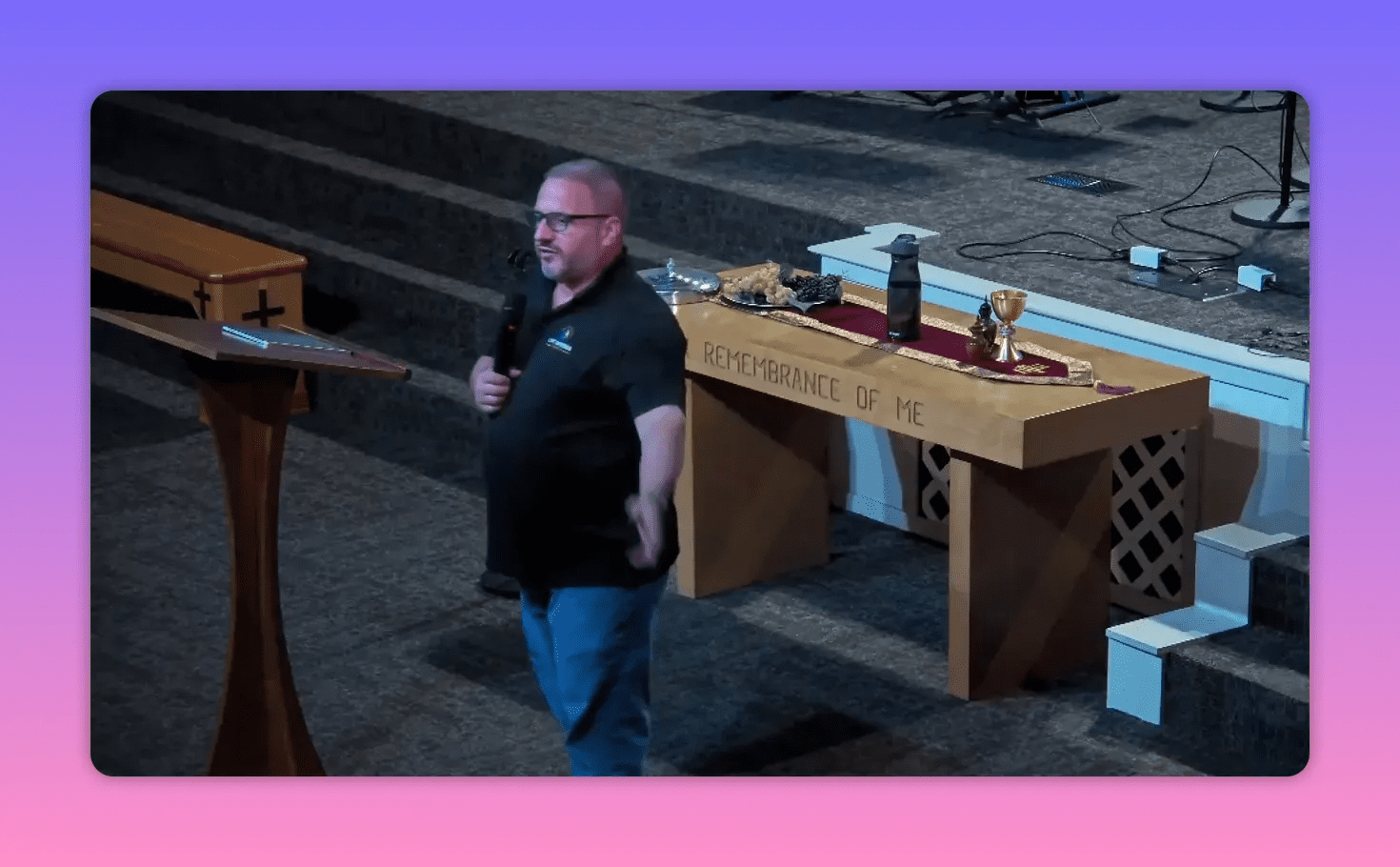 Clear frontal shot of a speaker by the communion table with 'Remembrance of Me' visible on the table