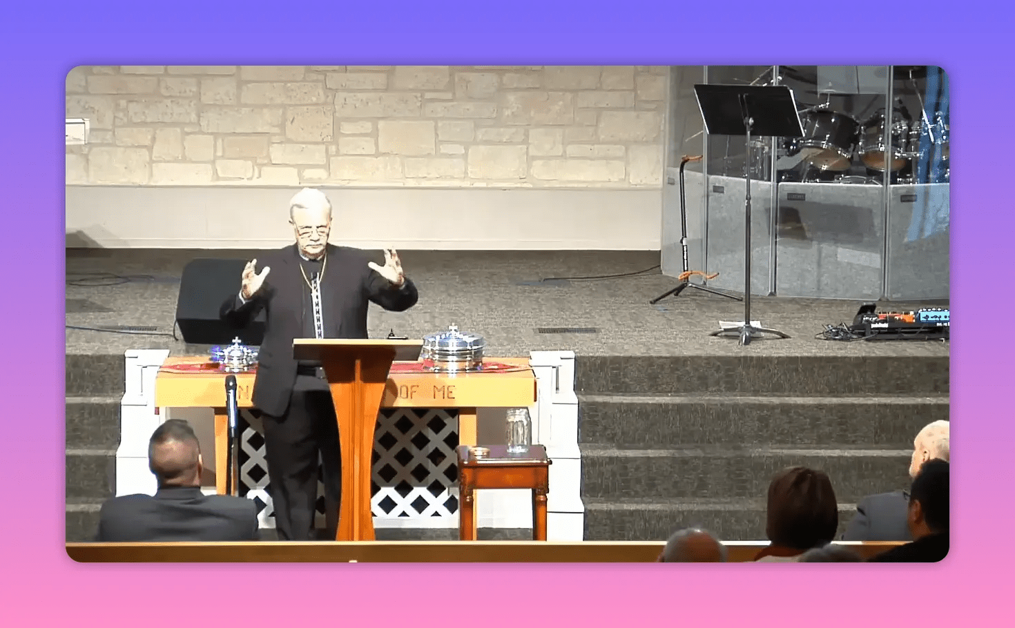 Church speaker at lectern with hands extended, making an emphatic gesture