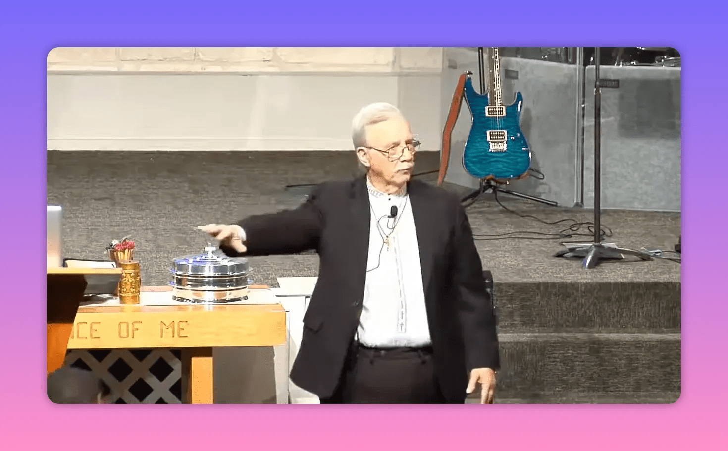 speaker pointing and gesturing beside pulpit with communion trays on table