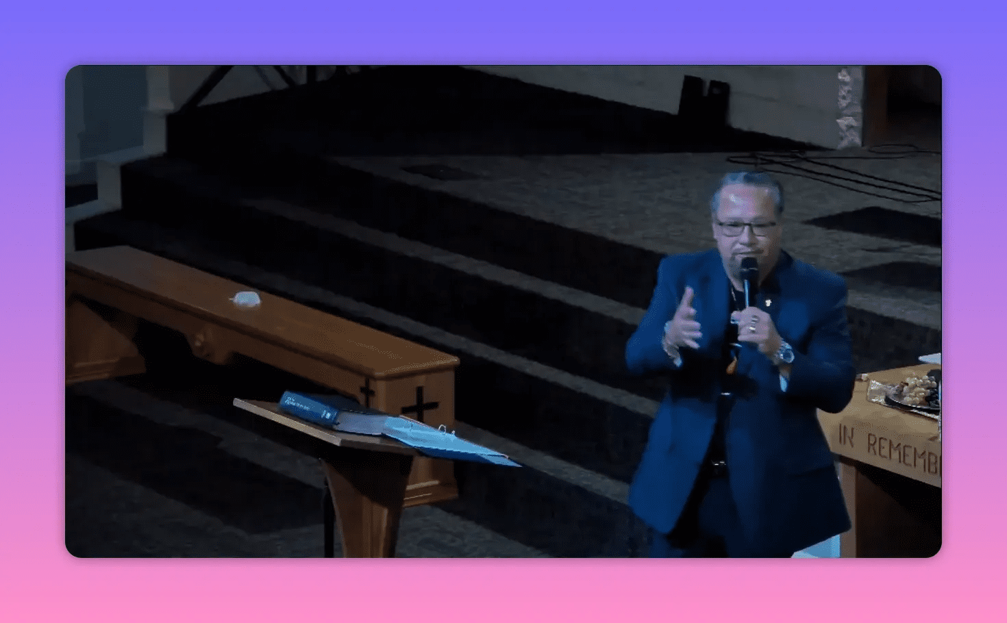 Speaker facing the congregation, hands reaching forward in an emphatic gesture while preaching from the pulpit