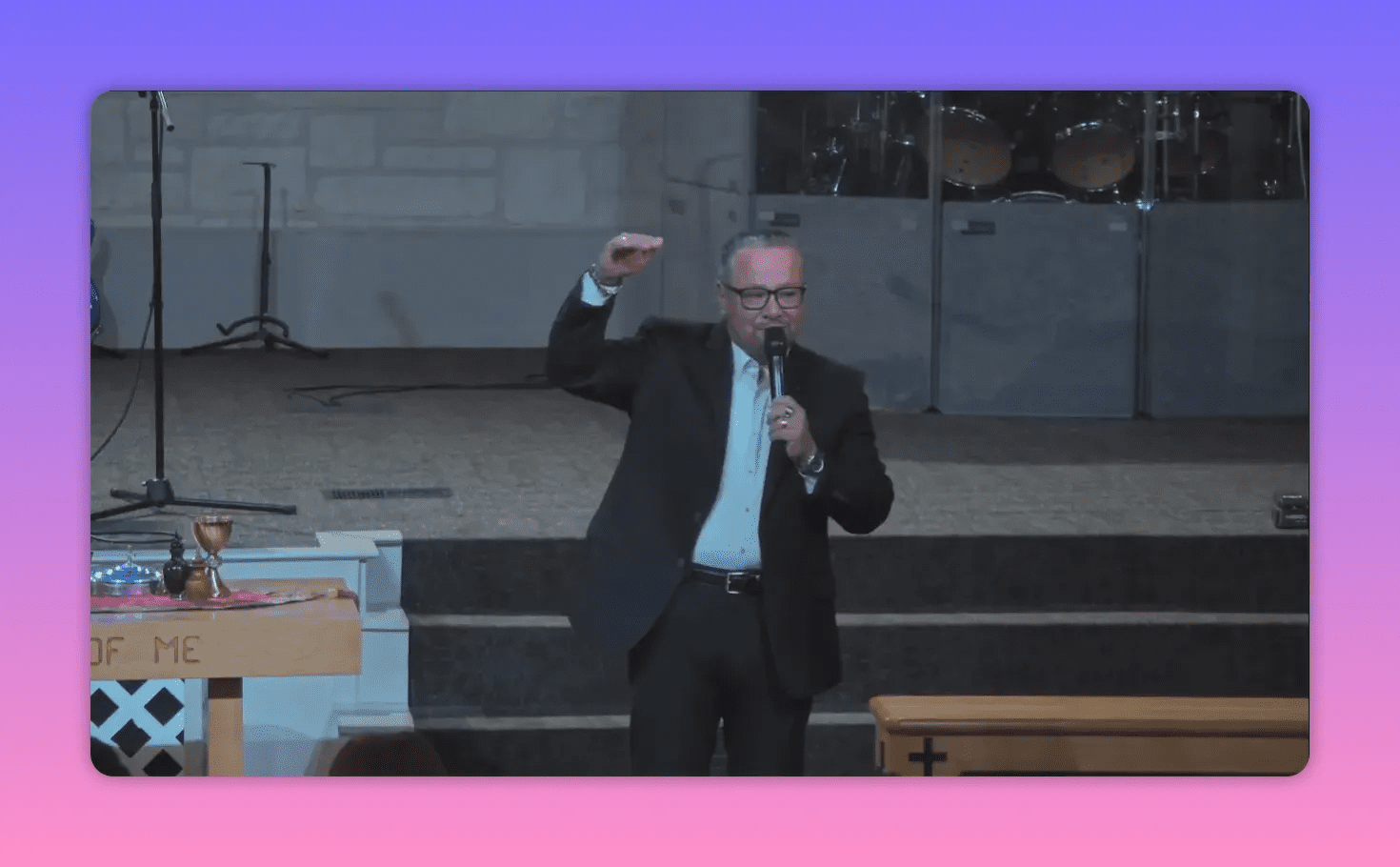 Pastor centered on stage with hand raised and microphone, illustrating a testimony in mid-sermon