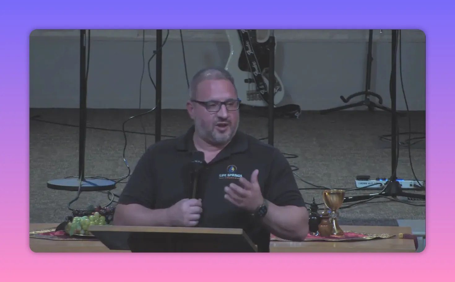 pastor speaking at pulpit with chalice and grapes prominently displayed