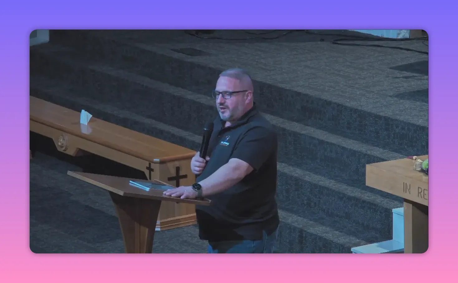 Pastor Brannan speaking at the pulpit holding a microphone, looking toward the congregation