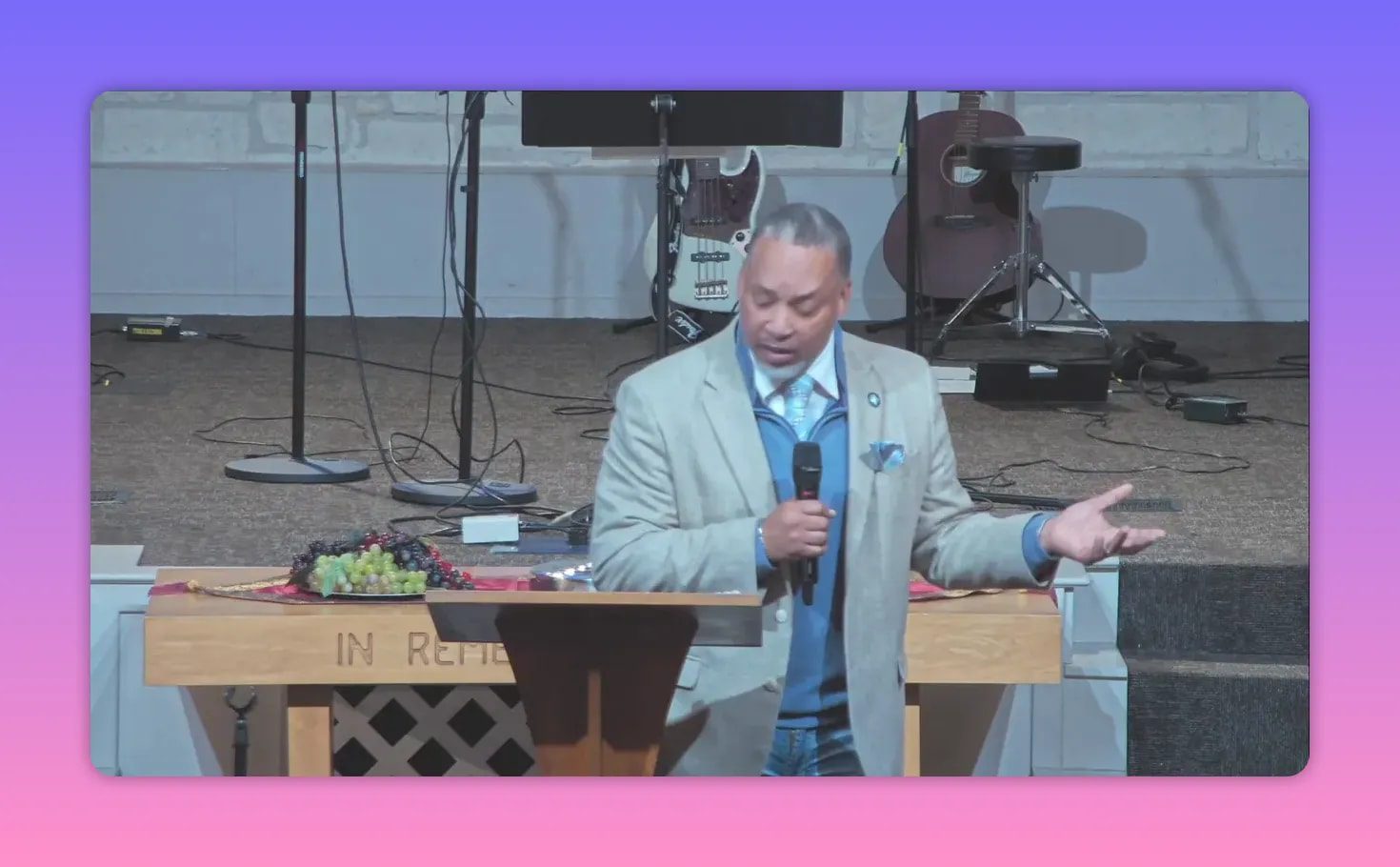 Pastor speaking from the pulpit with an open hand gesture and communion elements visible