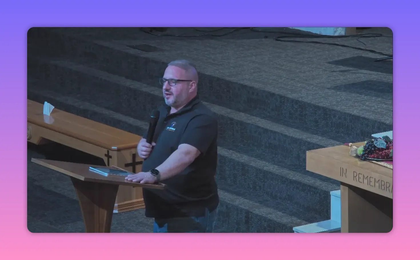 Pastor speaking into a microphone at a lectern with 'In Remembrance' on the altar