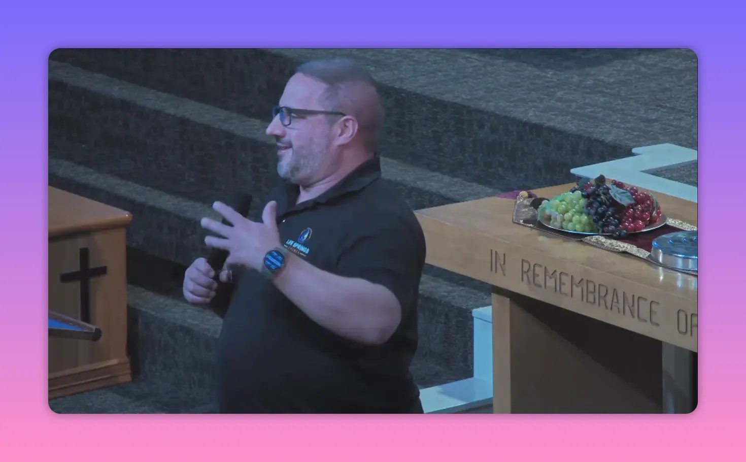 pastor gesturing beside communion table with a platter of fruit, smiling