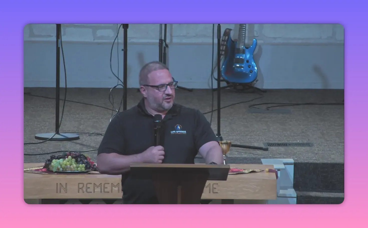 Preacher speaking at a lectern with a plate of fruit and a chalice on the communion table behind him