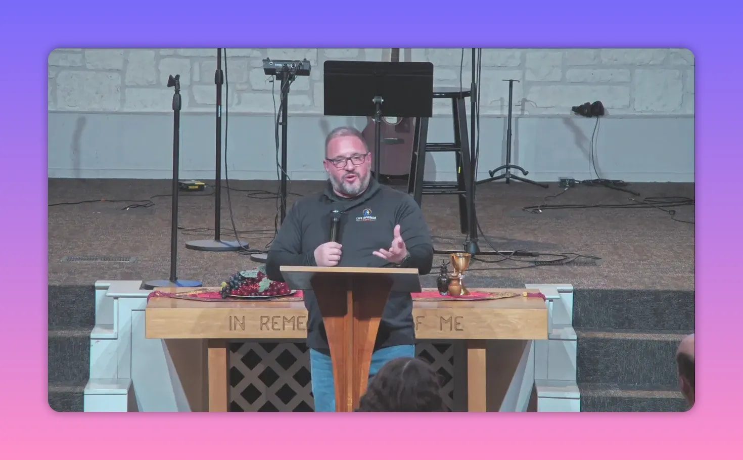 preacher gesturing at pulpit with communion elements on the table