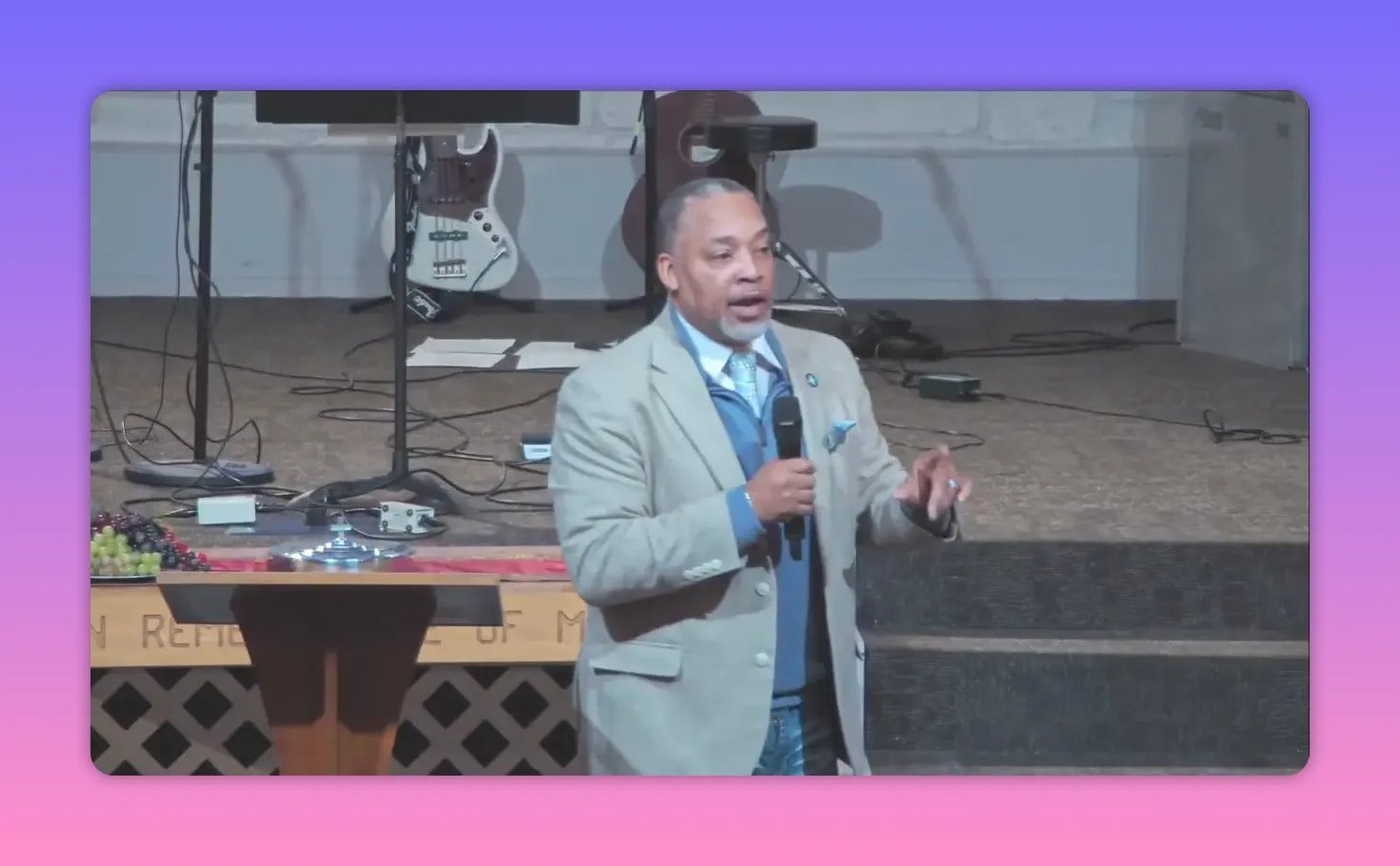 Speaker standing beside lectern gesturing with hand while holding microphone