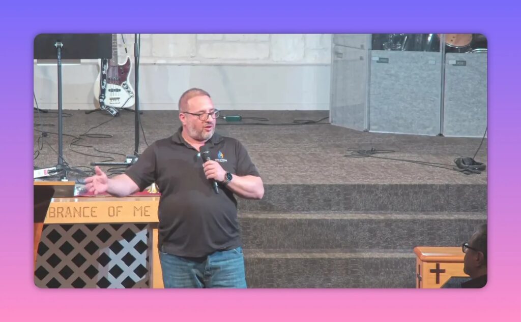 Speaker gesturing toward congregation with communion table and steps behind