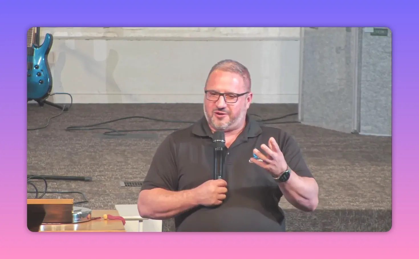 Church speaker holding a microphone with hand raised while teaching about Eden and God’s presence
