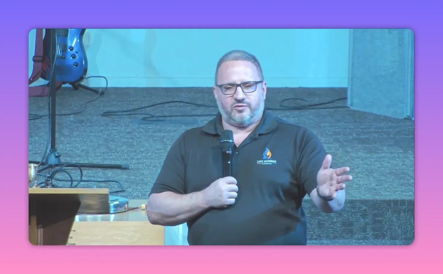 Church speaker holding a microphone with an open-hand gesture while teaching about discipleship