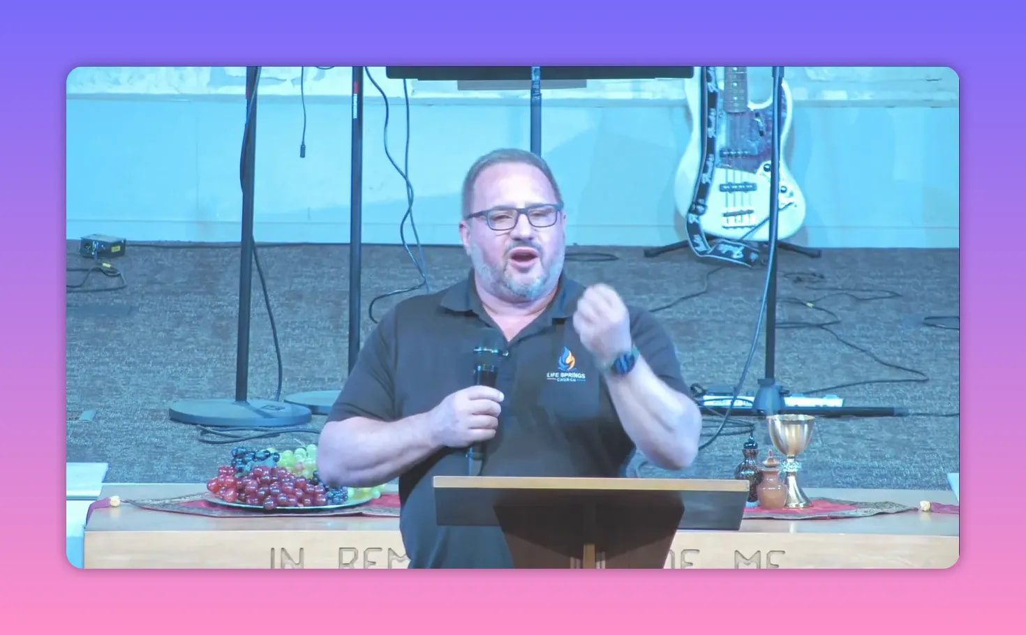 Church speaker gesturing while holding a microphone during a sermon about Jesus’ blood