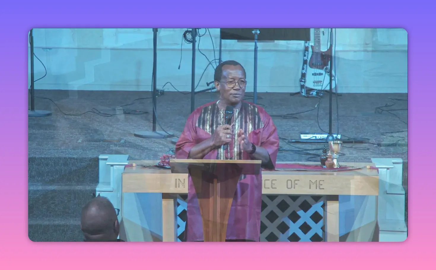 Church minister speaking at the pulpit with both hands gesturing while holding a microphone