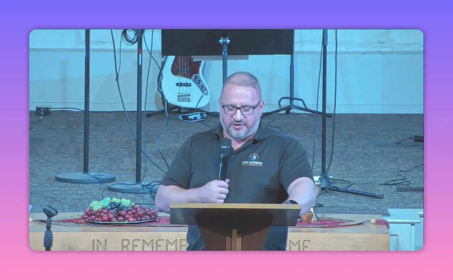 Pastor speaking at a lectern with microphone in front of a church stage