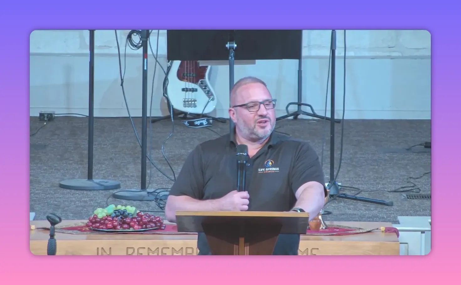 Pastor at a lectern speaking into a microphone during a sermon on looking unto Jesus