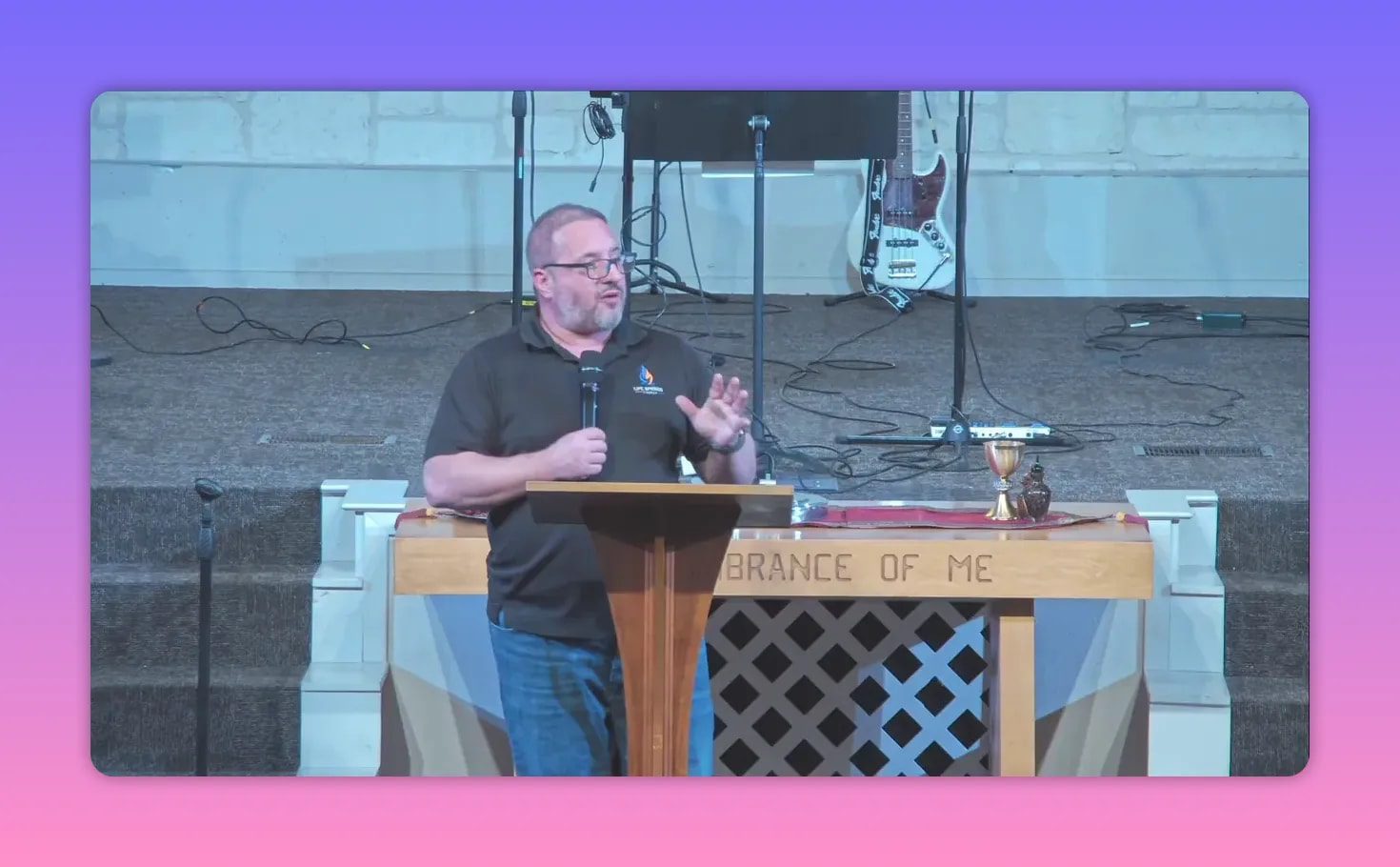 Pastor speaking at a lectern in front of a church stage setup with instruments