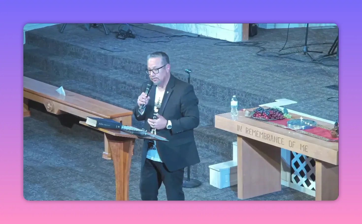 Pastor teaching next to Communion table with elements and altar backdrop