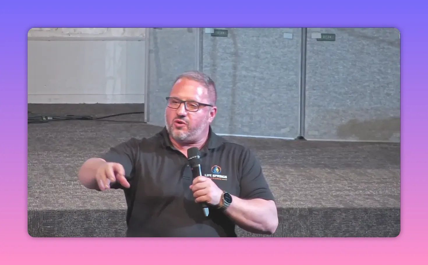Outdoor church speaker pointing while holding a microphone during a sermon