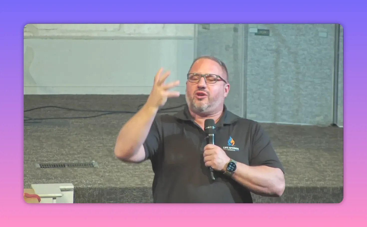 Speaker with hand raised while holding a microphone, teaching about faith over fear