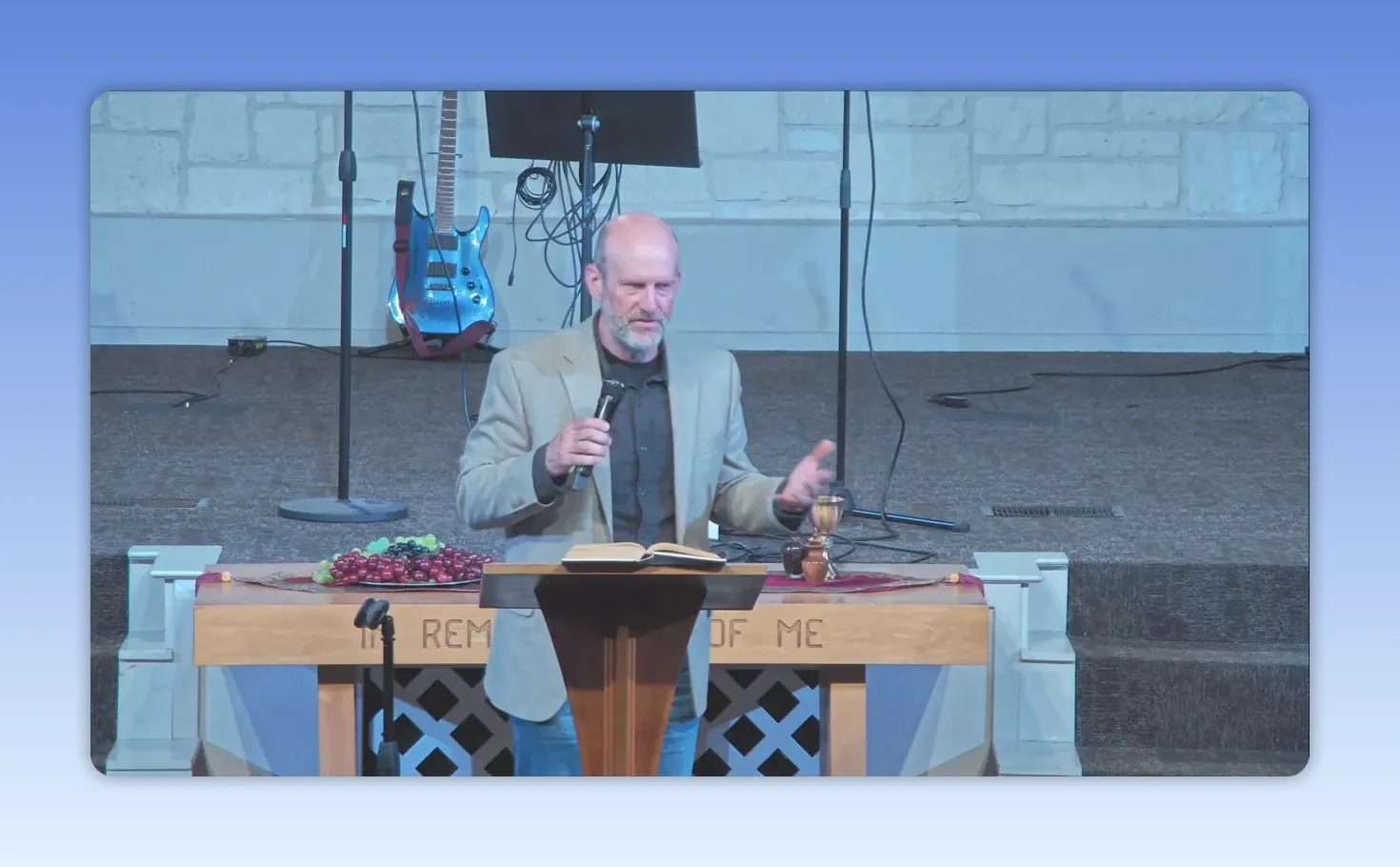 Pastor gesturing while speaking at a church podium with an open Bible